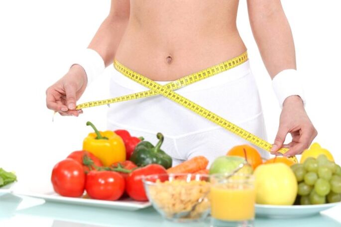 ragazza che misura la vita sullo sfondo dei generi alimentari